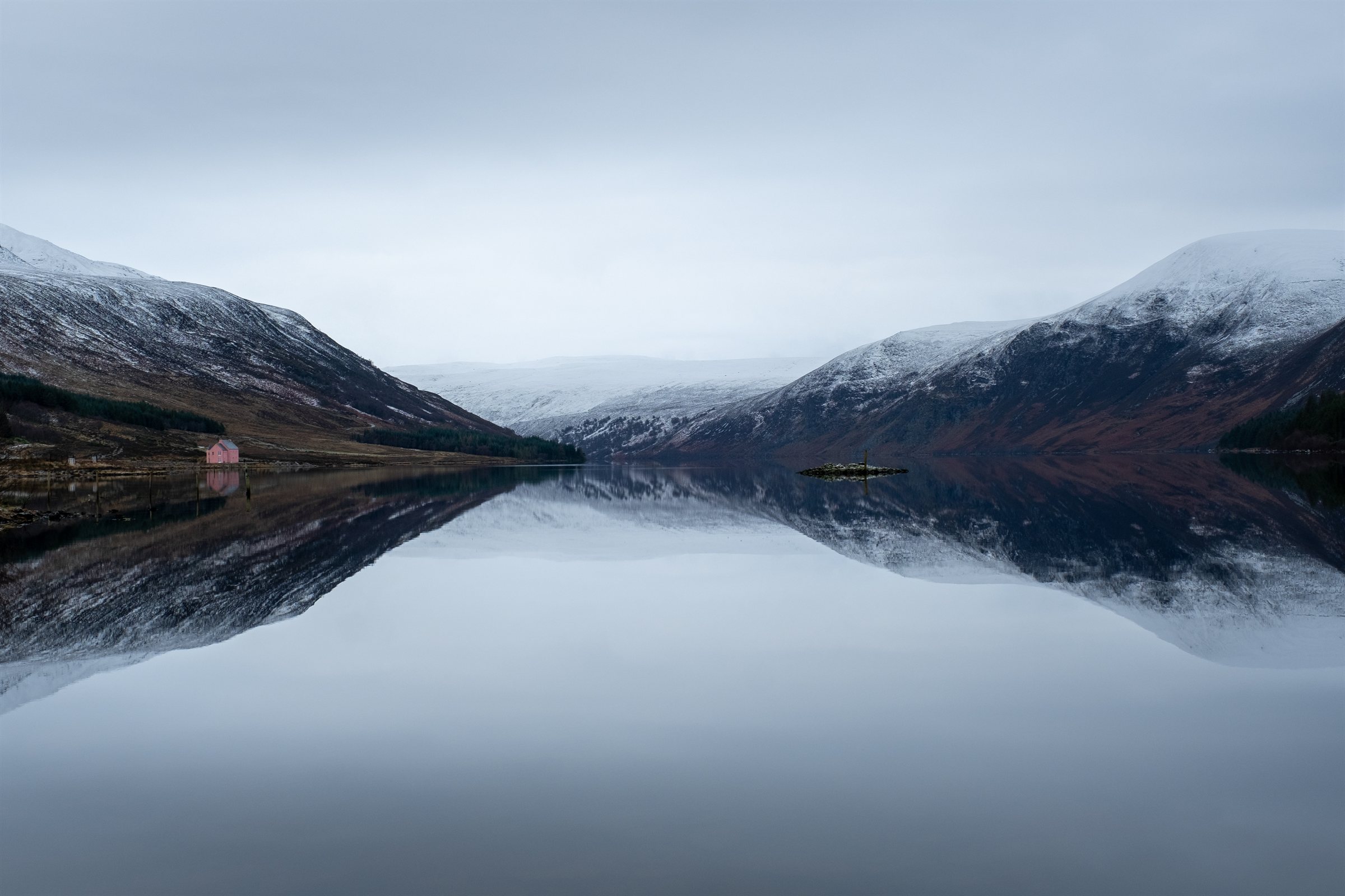 Snowy hills mirrored in a perfectly still loch