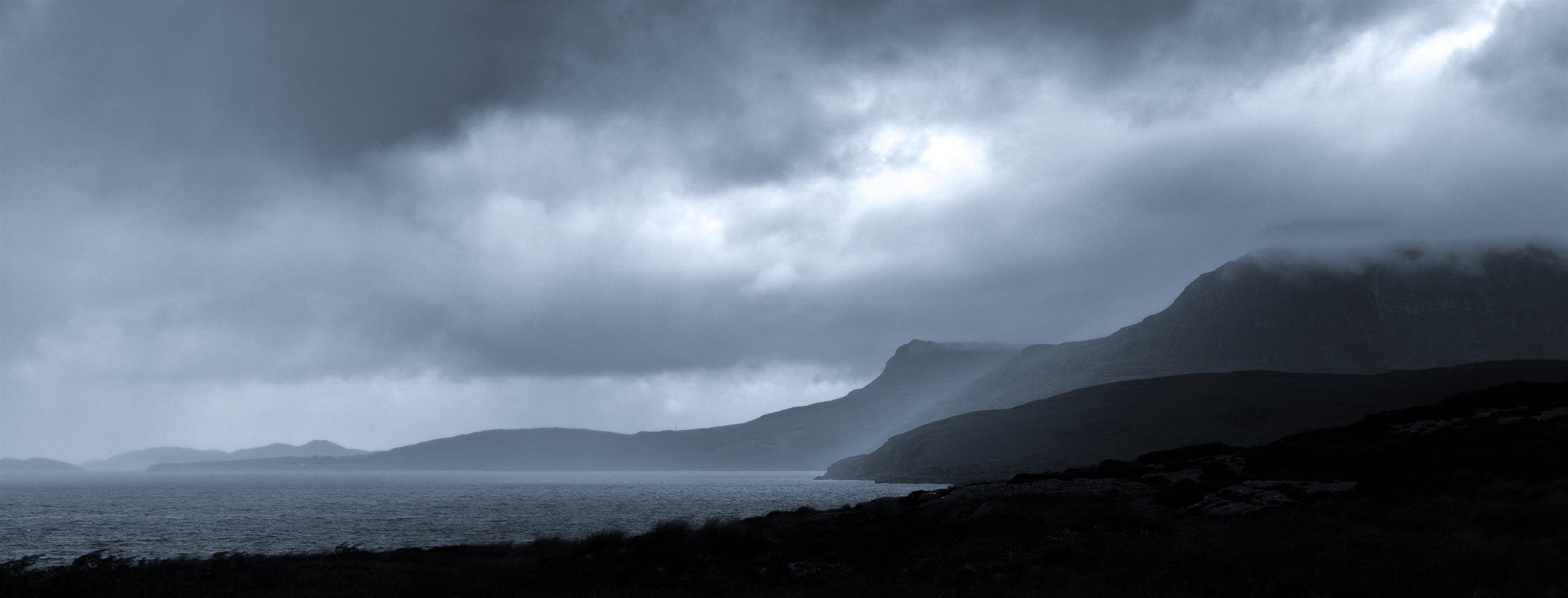 Grey cloud rolling over the hills above a dark loch