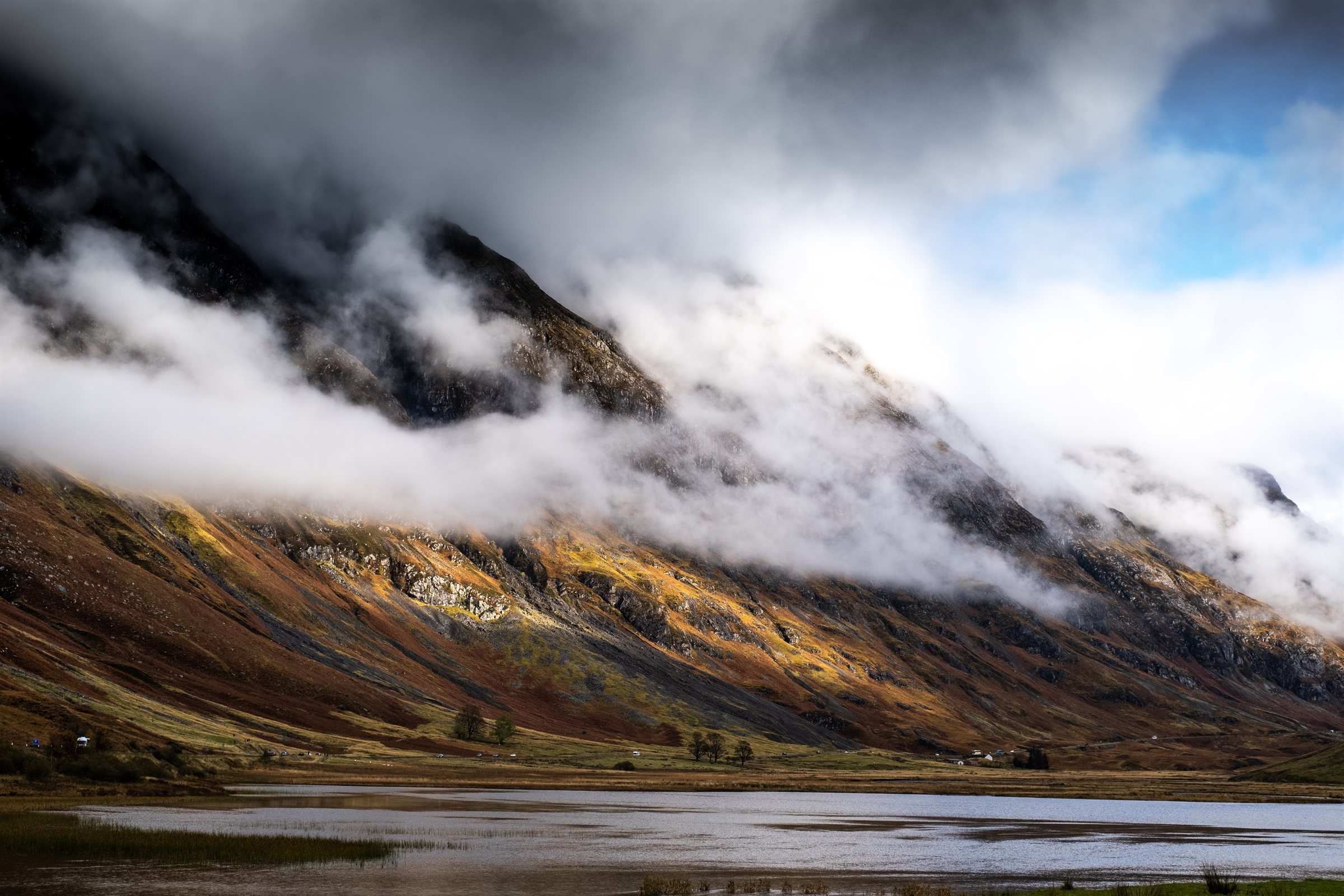 Cloud spilling over a steep mountainside above a loch