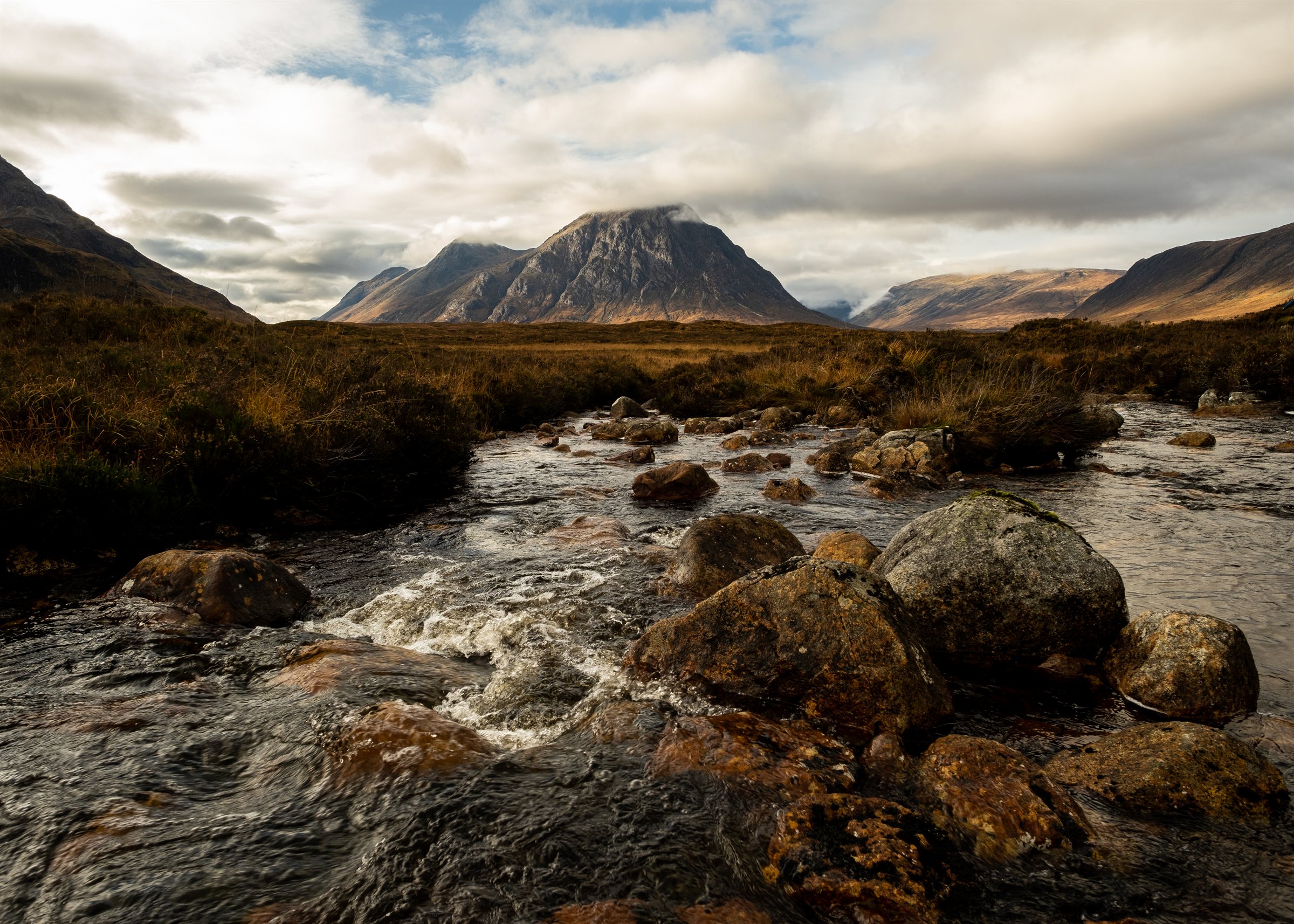 A rocky river leading towards peaked mountains