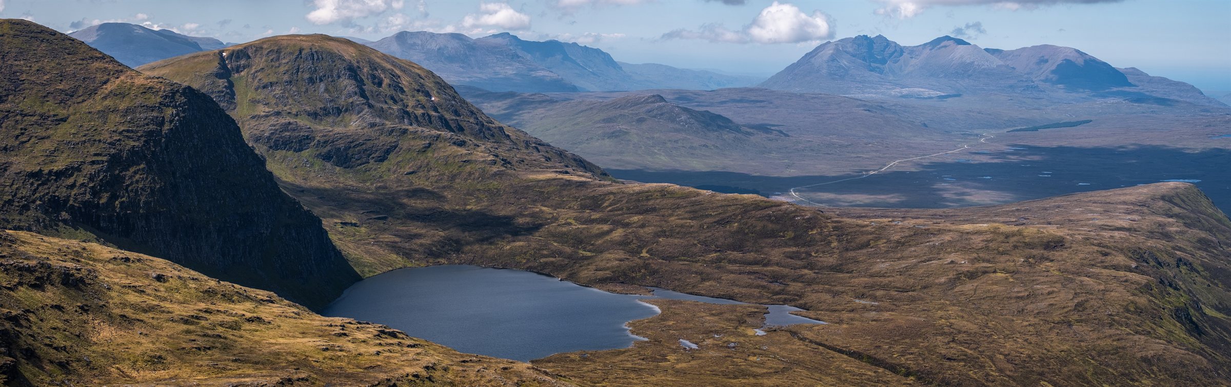 A lochan among rocky highland hills, mountains on the horizon