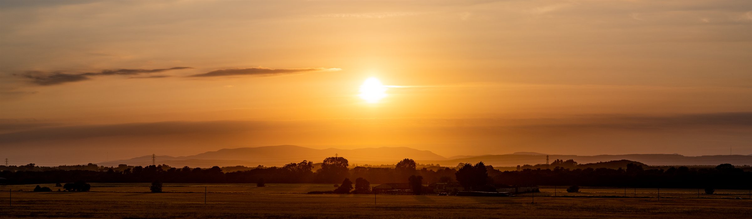 The sun setting in orange over a dark, flat horizon