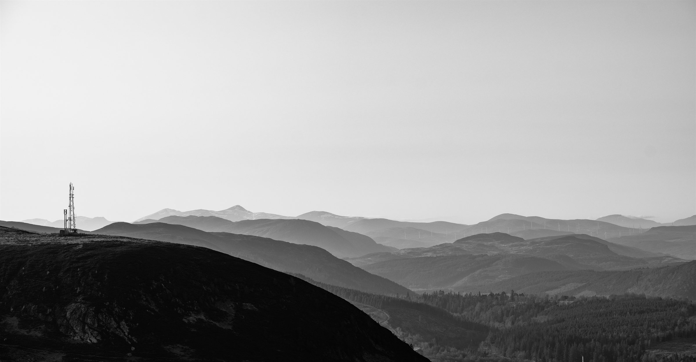 Rolling hills fading into haze, a pylon on the ridge