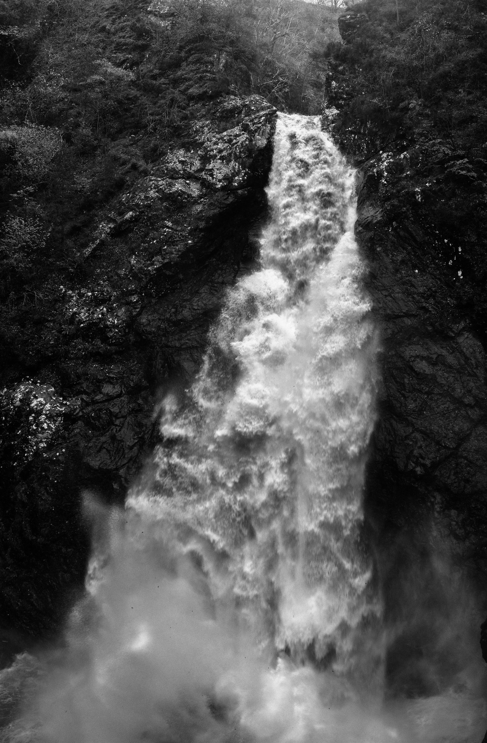 A waterfall plunging down a dark wooded gorge