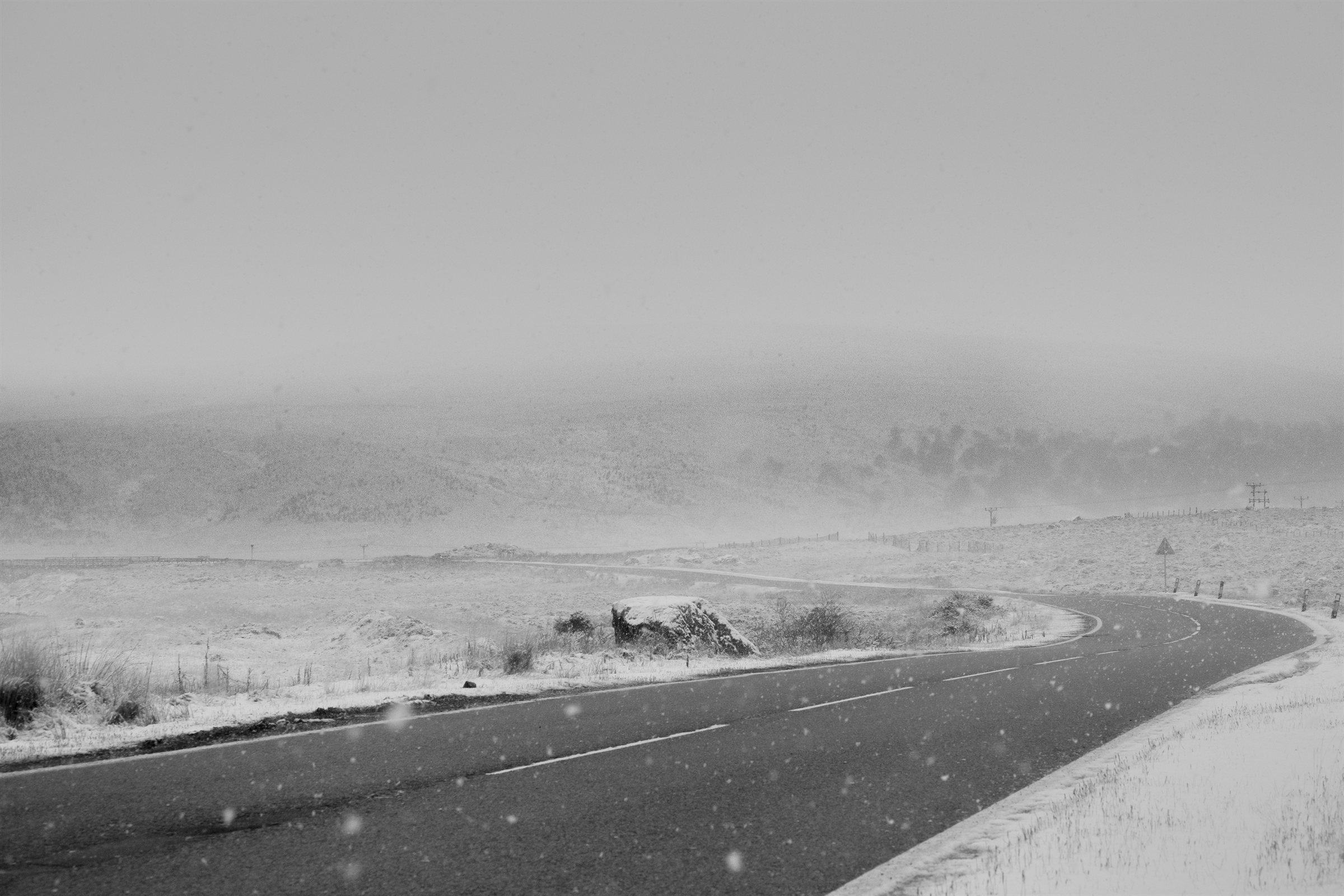 A road curving through a snowstorm on the moor
