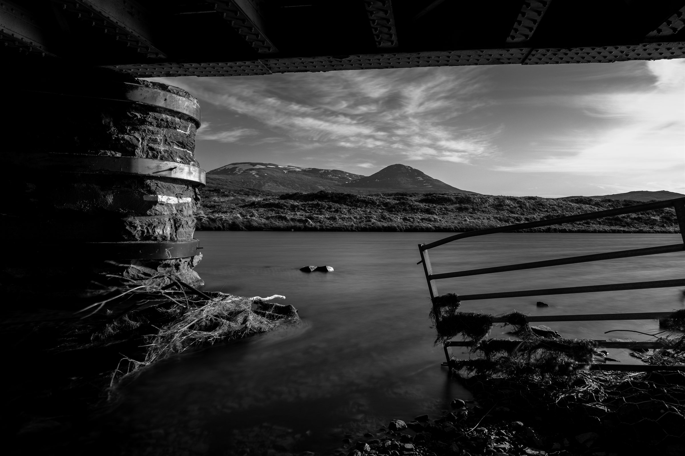 Looking out from a dark shelter across a loch to the hills