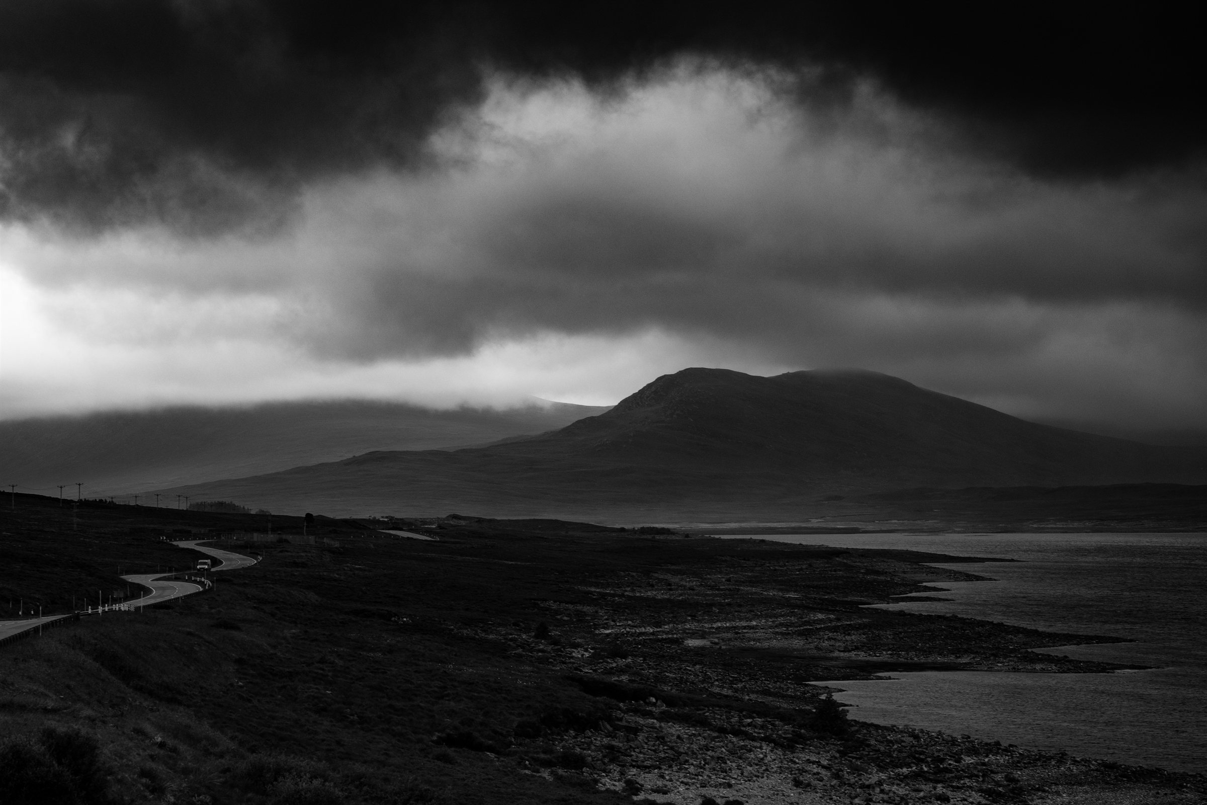 Storm clouds over a mountain and a winding moorland road