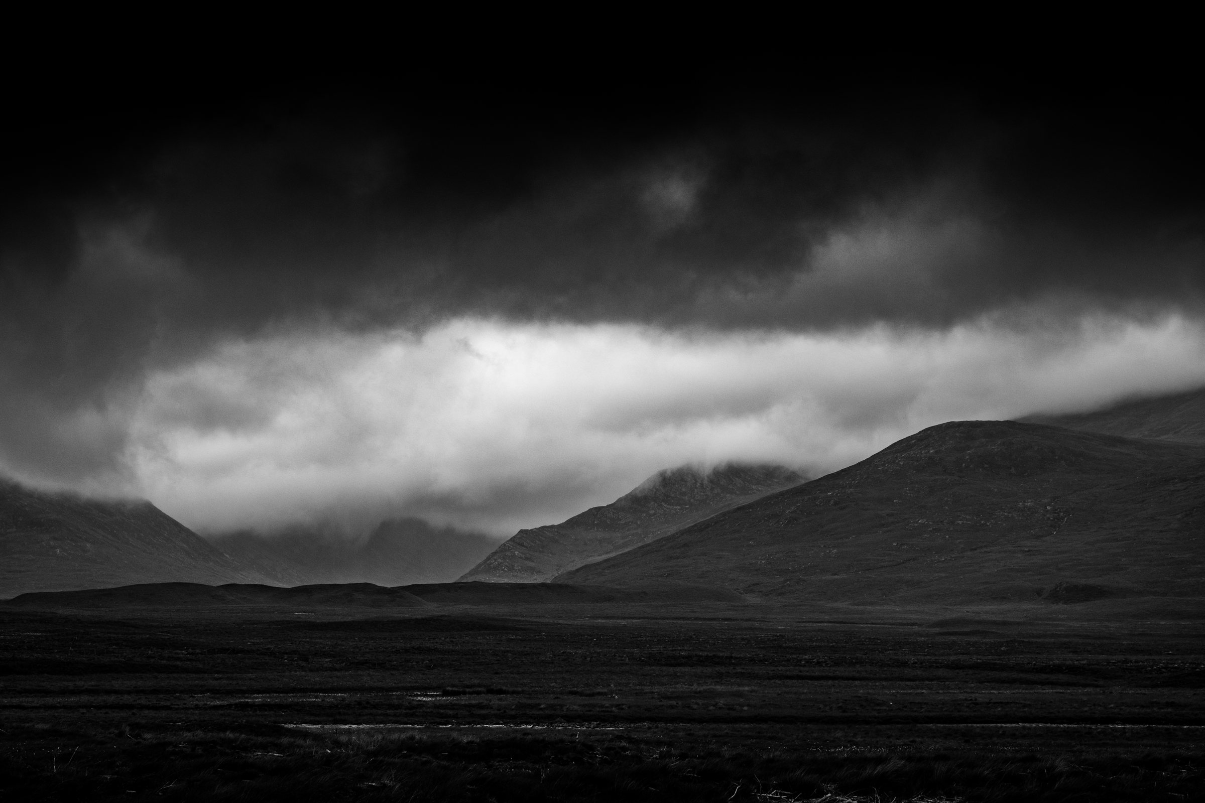 Light breaking under heavy cloud across the hills