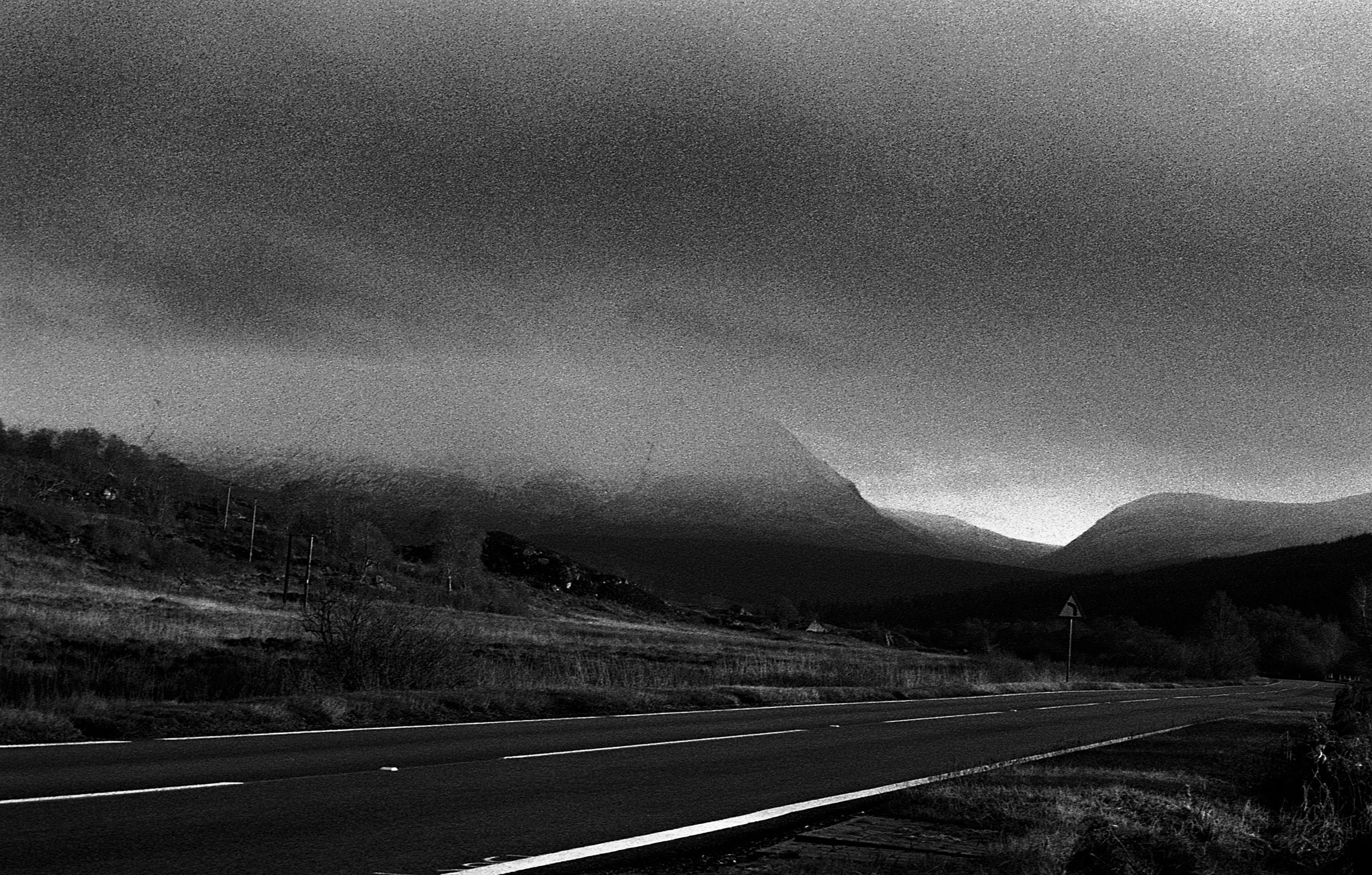 A road beneath a mountain lost in low cloud