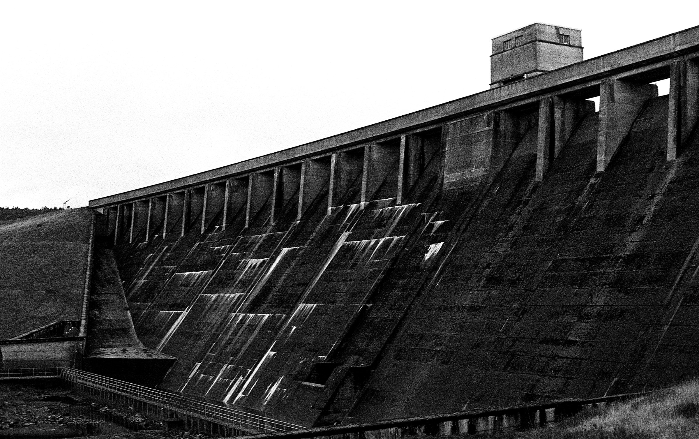The face of a concrete dam, streaked with water