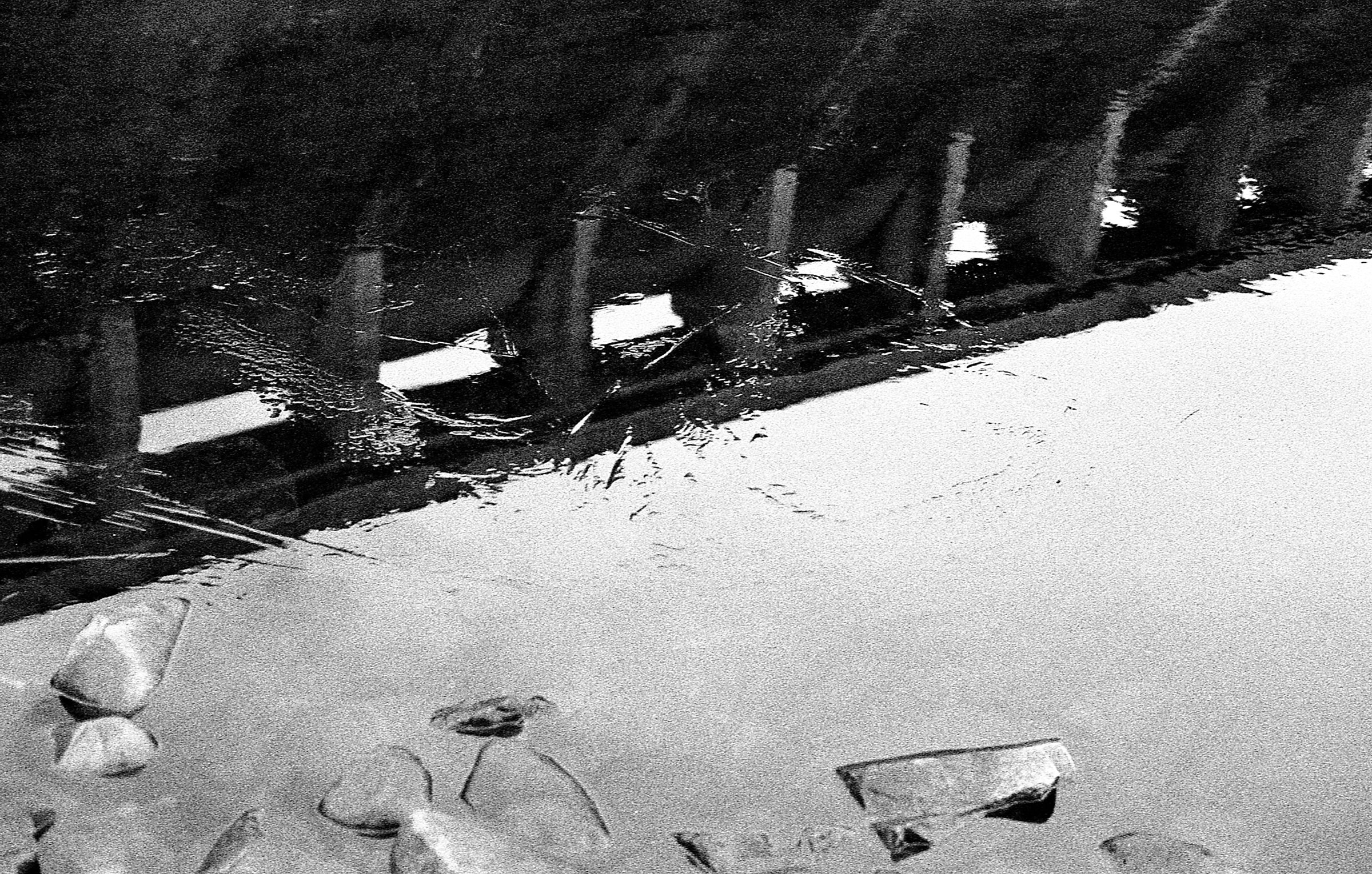 The dam reflected upside down in still water beside the stones
