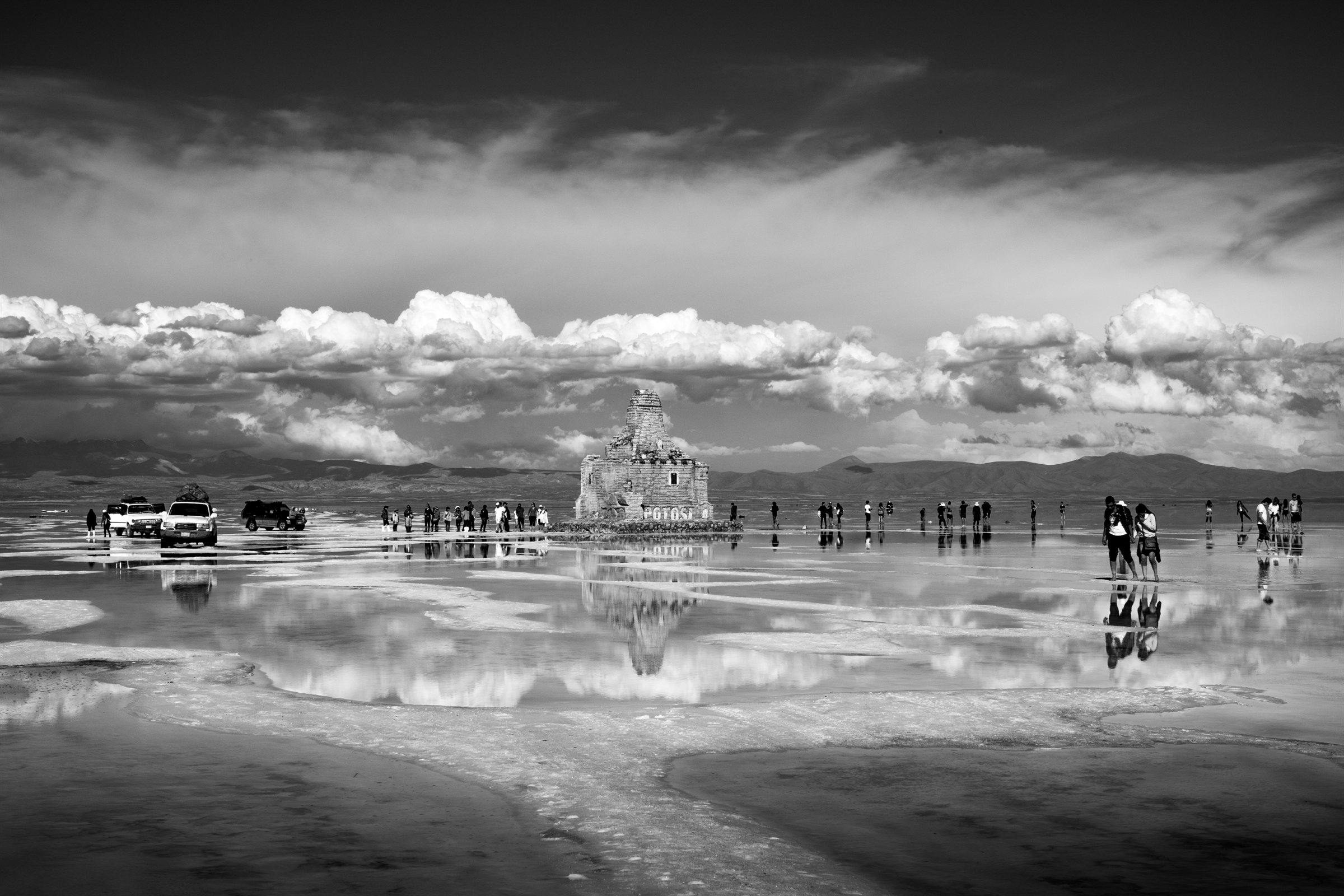 Clouds and distant jeeps reflected on the salt flats