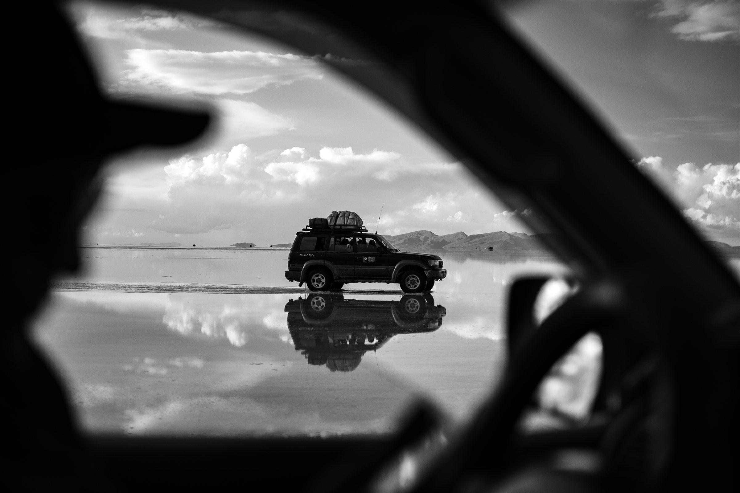 A jeep seen past a silhouetted figure in a car window