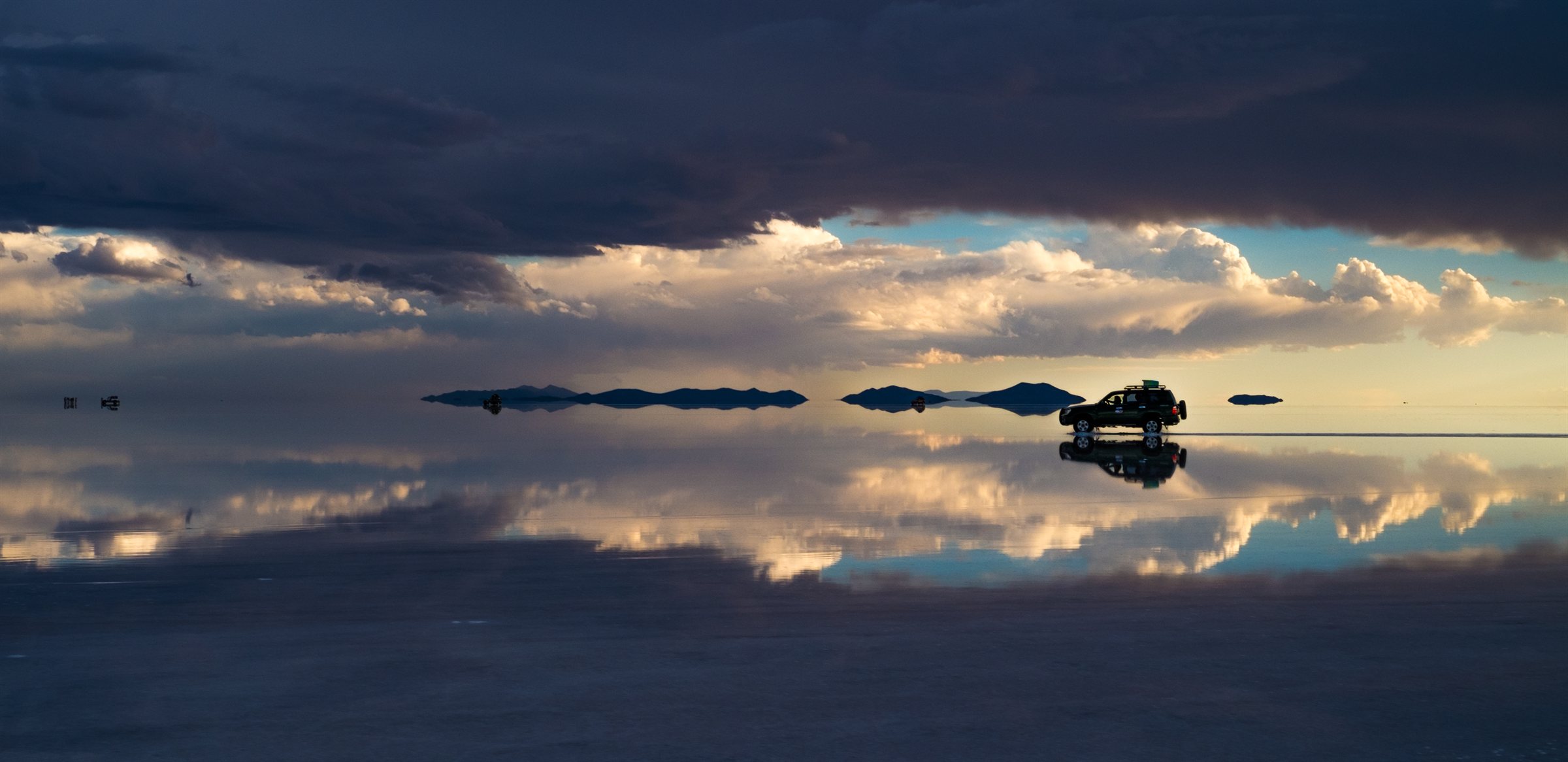 A band of light on the horizon over the mirrored salt flats