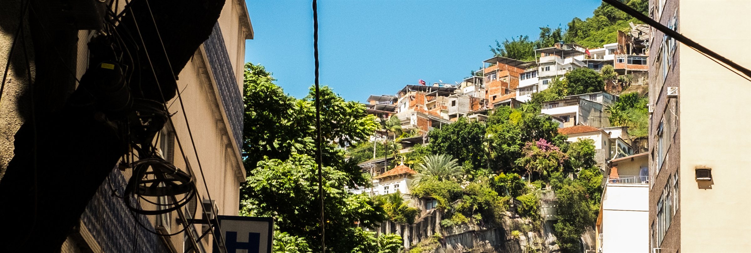 Houses climbing a green hillside under a blue sky