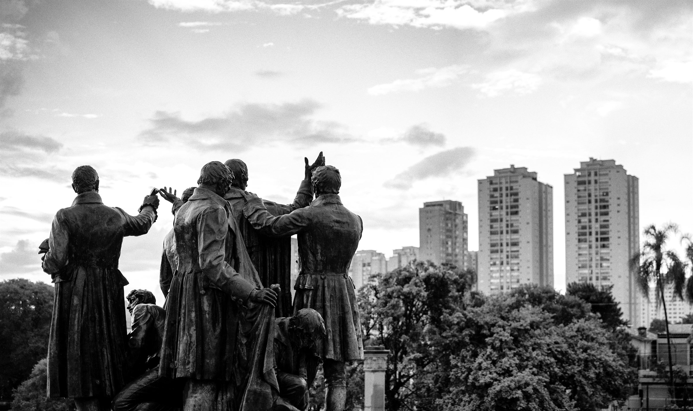 Statues on a monument with tower blocks behind