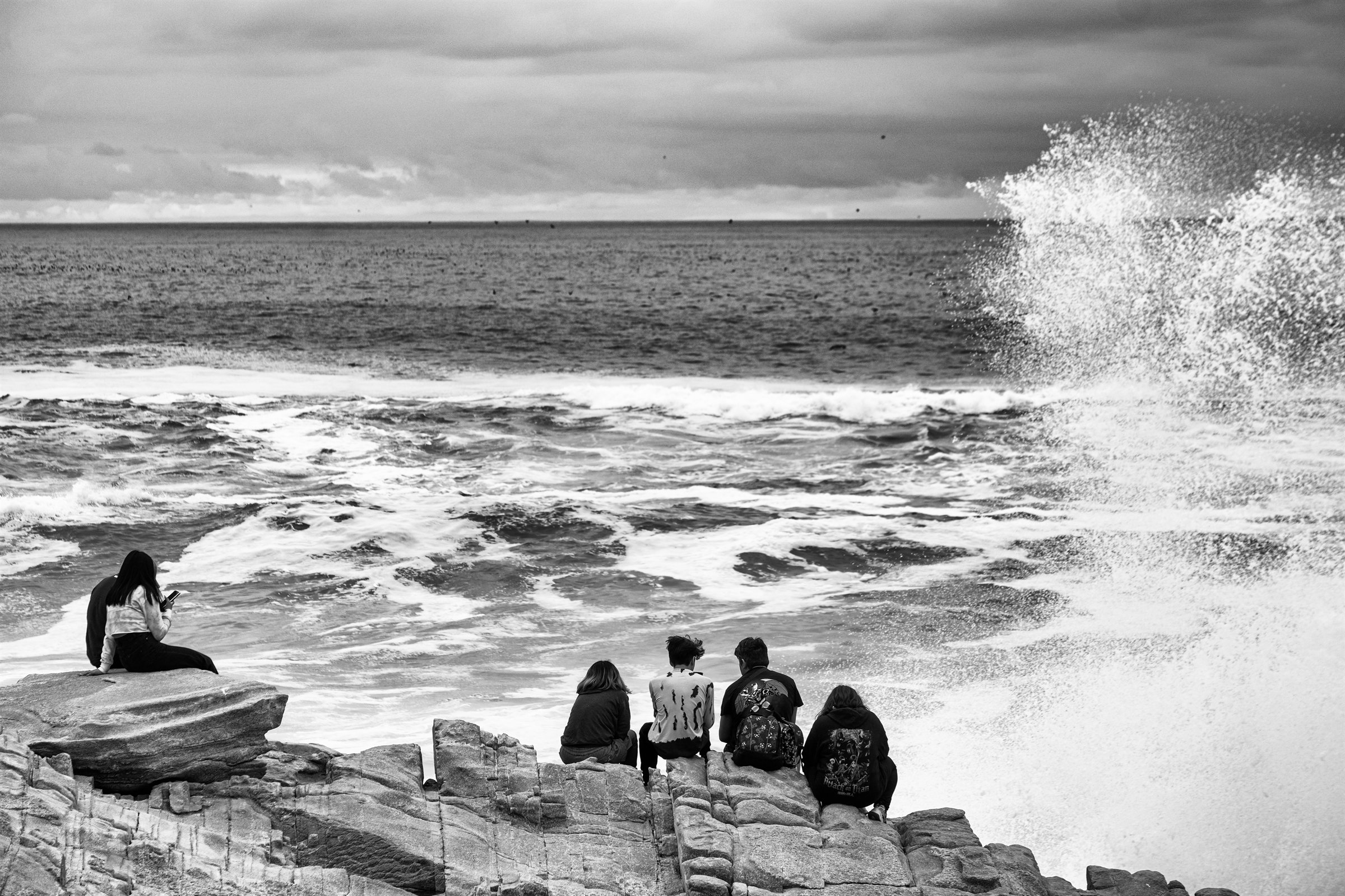 People watching waves crash over the rocks